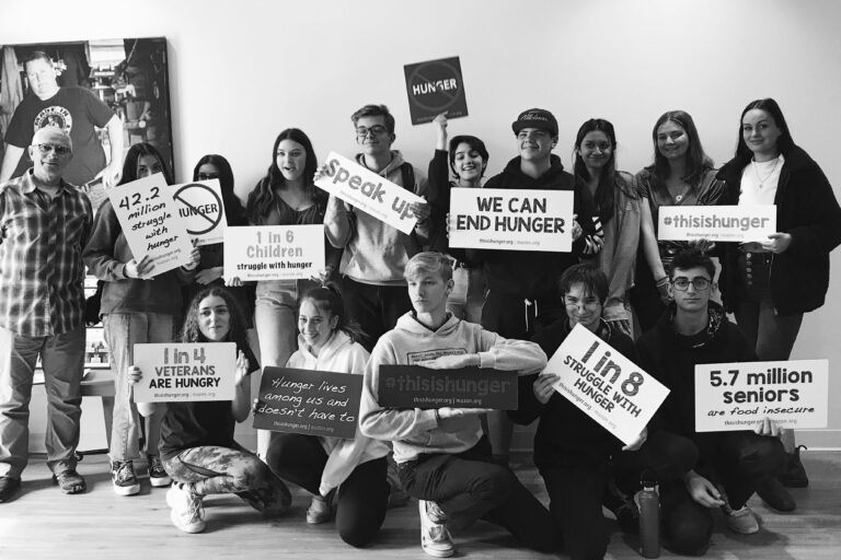 Group of kids with signs posing.