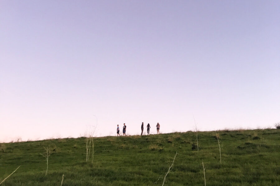 purple sky over people on a hill in the distance.