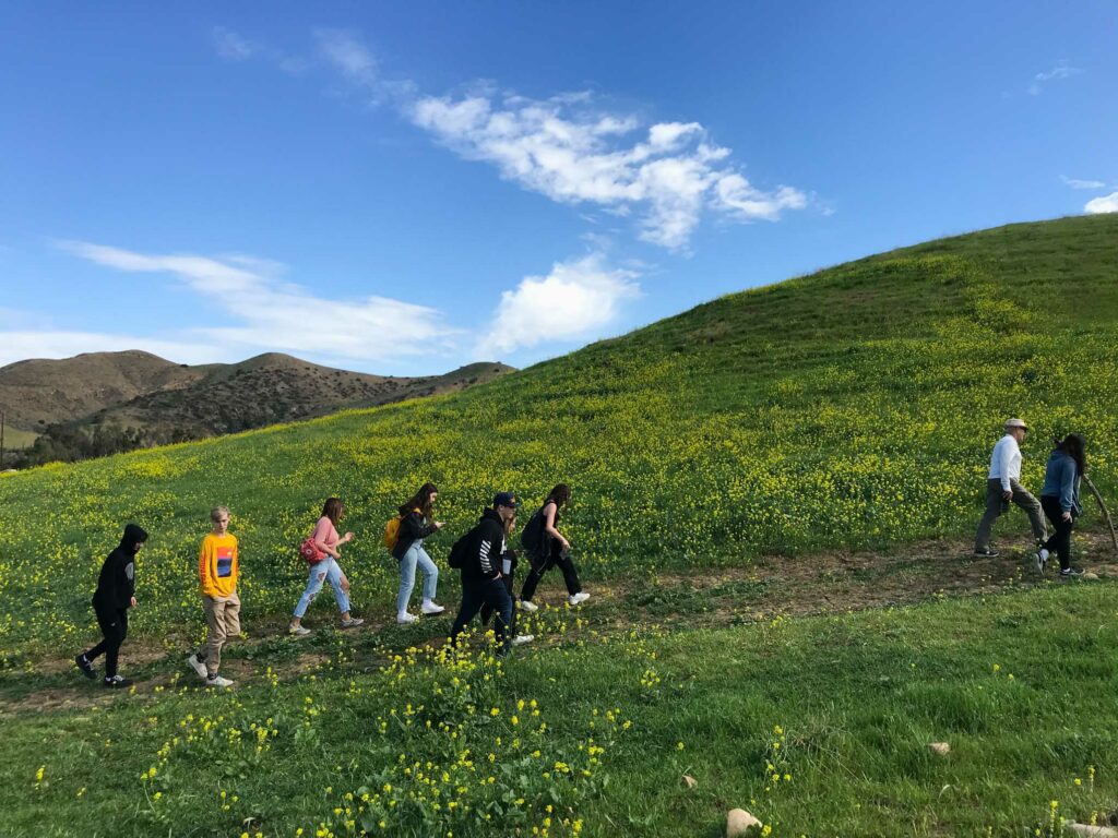 teens walking up the side of a grassy hill.