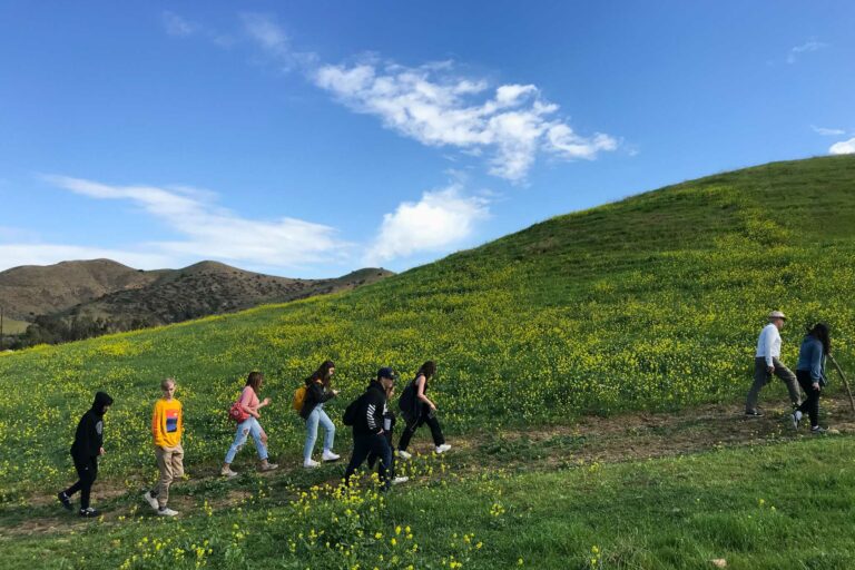 teens walking up the side of a grassy hill.