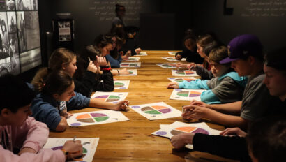 young teens working at a table in a dark room.